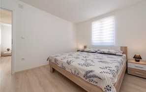 A bedroom with a bed, bedside tables, and a window with blinds. - Cozy home in Pakostane (Pakostane)