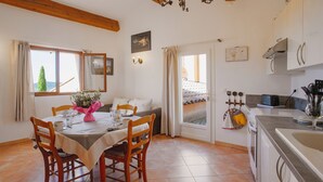 A dining area with a table set for four, wooden chairs, a vase of flowers, and a view through a window. - SPACIOUS 3 ROOMS APT IN LARGE GARDEN HOUSE, WIFFI, CLASS 3 *, 1km from the beach  (le lavandou)