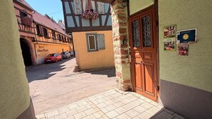 L’entrée d’un hôtel, avec un pilier en pierre, une porte en bois et un trottoir dallé menant à la rue.