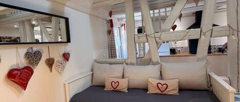 A bedroom with a loft-style bed, a hanging light fixture, a mirror, and heart-shaped decorations.