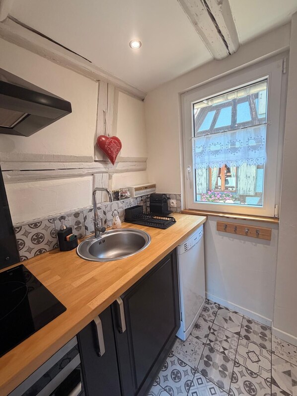 A compact kitchen with a wooden countertop, a stainless steel sink, and a window with a view of the outside.