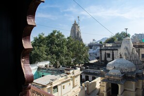 A view of a temple complex with multiple structures, including a prominent tower and domed buildings, surrounded by trees and other buildings. - Banjara Heritage (Udaipur)