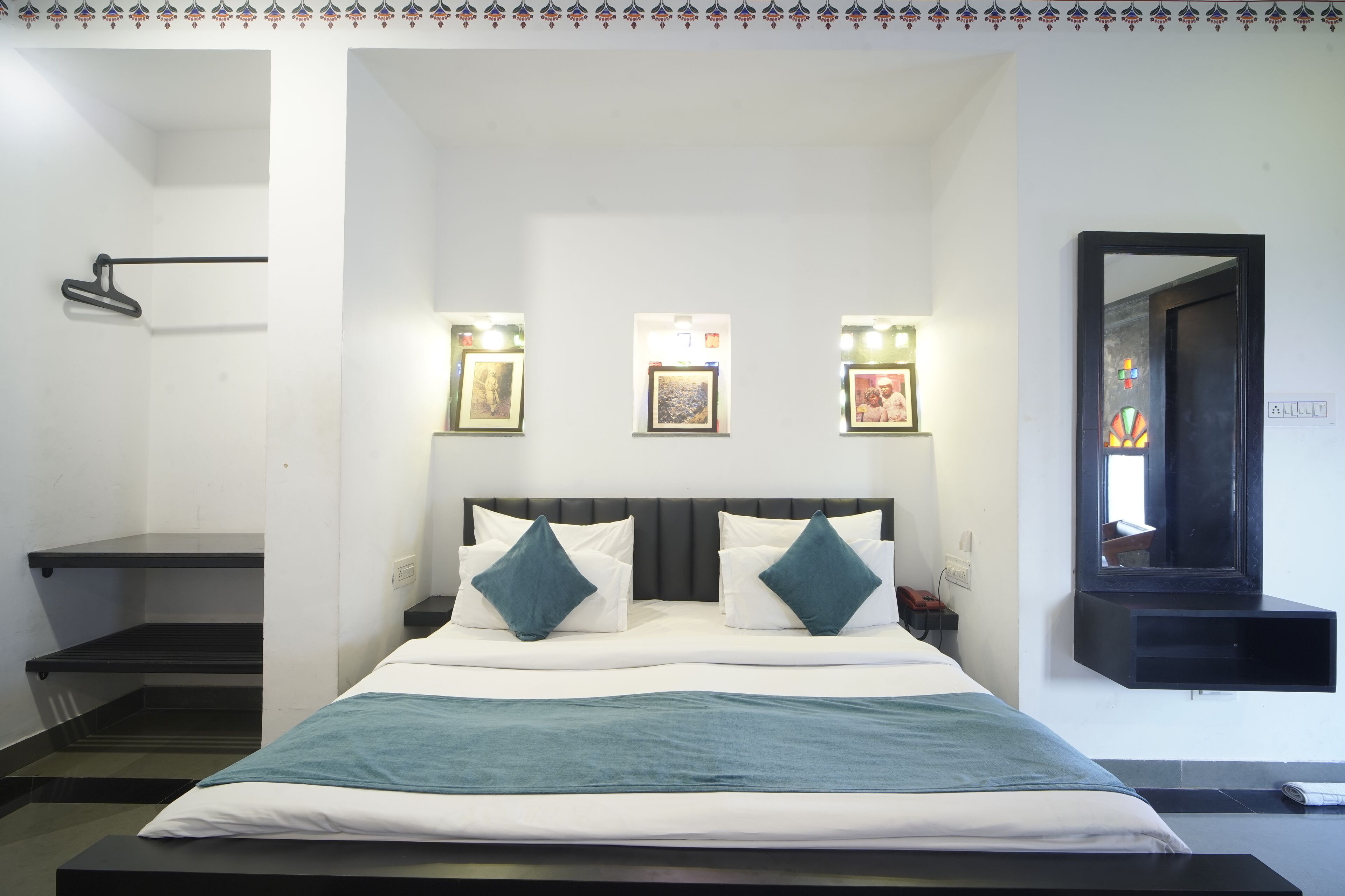 A bedroom with a bed, bedside tables, a mirror, and wall-mounted lights.