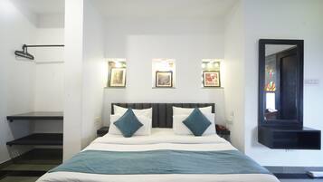A bedroom with a bed, bedside tables, a mirror, and wall-mounted lights.