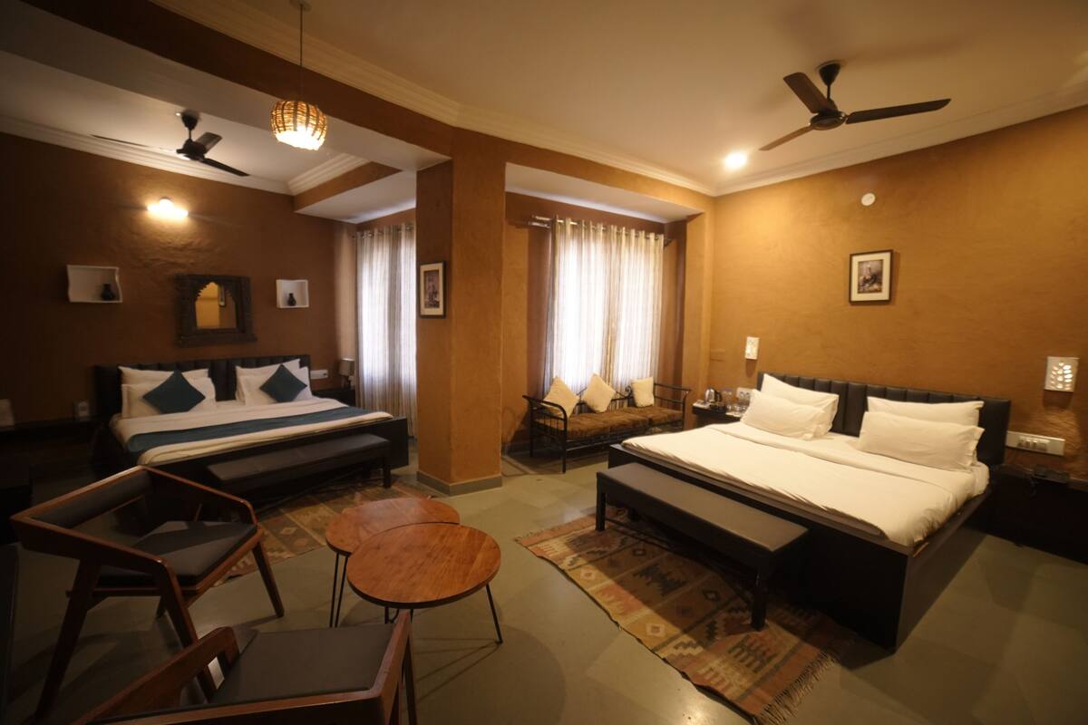 Una habitación de hotel con cama, sofá, una mesita y ventilador de techo.