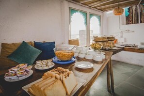 A breakfast buffet with various food items and a cozy seating area with cushions. - Banjara Heritage (Udaipur)