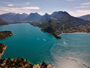 Vista panorâmica de um lago rodeado por montanhas, com uma pequena cidade e céu limpo.