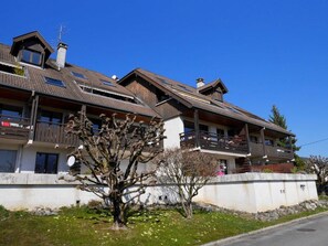 A row of chalet-style buildings with wooden balconies and a clear blue sky.