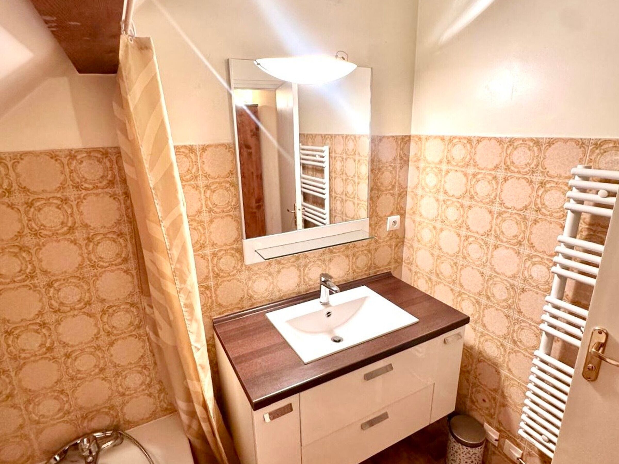 A bathroom with a sink, mirror, and towel rack.