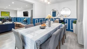 Un'area pranzo moderna con una tovaglia fantasia, pannelli murali blu e bianchi e una ventola a soffitto.