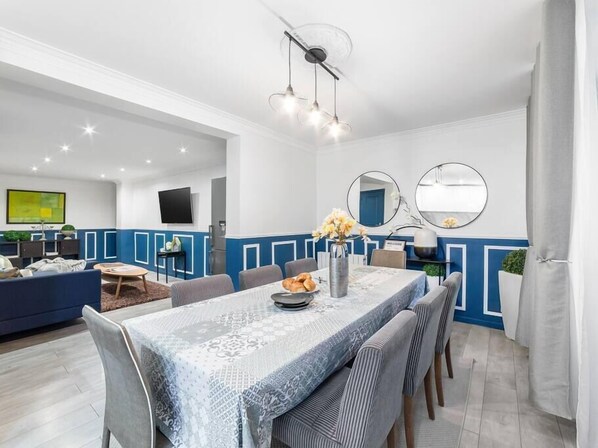 A modern dining area with a patterned tablecloth, blue and white wall paneling, and a ceiling fan.