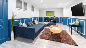 Un soggiorno moderno con un divano blu, un tavolino da caff è e una TV a parete.