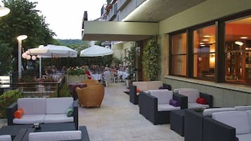 Un'area patio esterna con mobili in vimini, ombrelloni e tavoli.