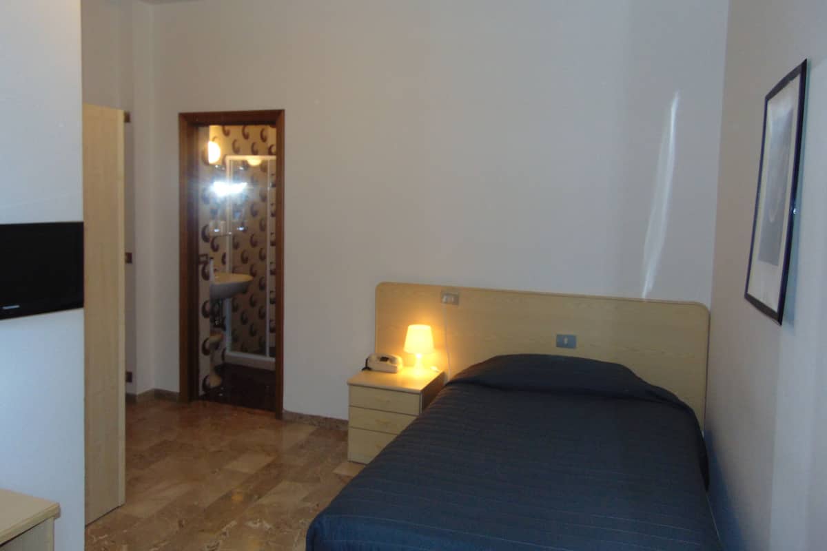 Quarto com cama, mesa de cabeceira e espelho.