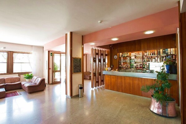 Un vestíbulo de hotel con recepción, zona de estar y bar.