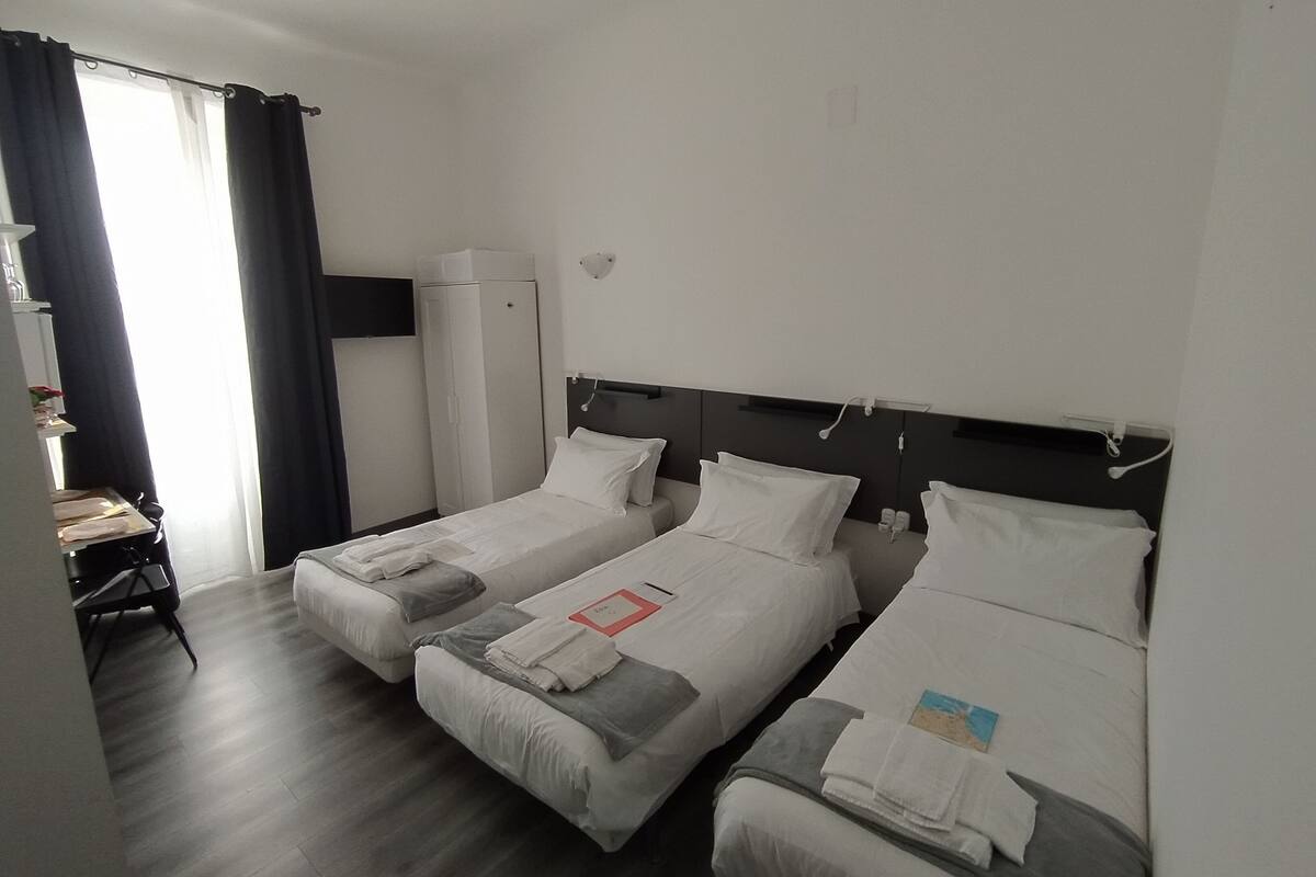 A hotel room with two single beds, a desk, and a wardrobe.