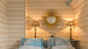 Ein gemütliches Zimmer mit einem Bett, zwei Lampen und einem Spiegel mit Sonnenstrahlendesign an der Wand.