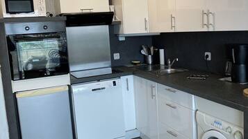 Una cucina moderna con mobili bianchi, forno integrato, microonde, lavastoviglie e lavatrice.
