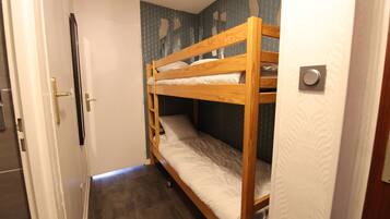 A bunk bed in a room with a door, a patterned wall, and a tiled floor.