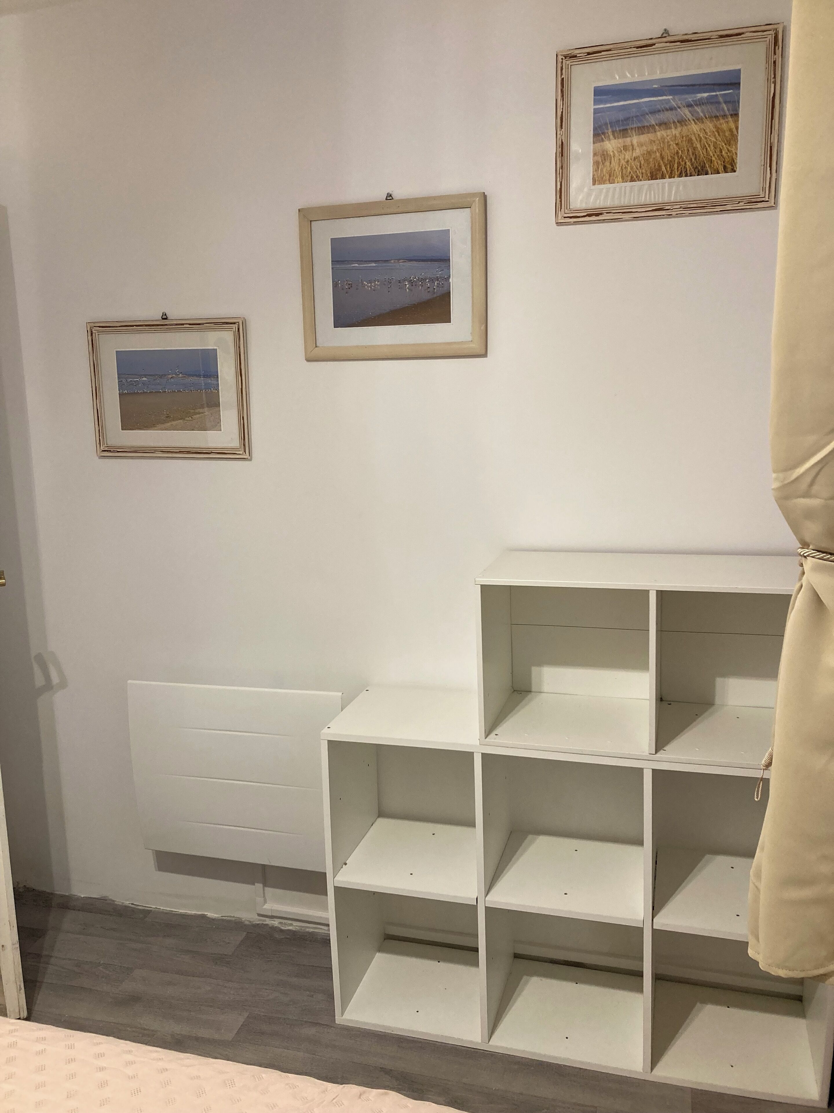 Ein Zimmer mit weißen Regaleinheiten und drei gerahmten Bildern an der Wand.