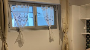 Un dormitorio con una cama, una ventana con cortinas y un armario.
