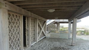 A covered outdoor area with a wooden structure, lattice panels, and a sandy ground. - Authentic chalet on stilts facing the sea (15 m) - 4-star services (gruissan)