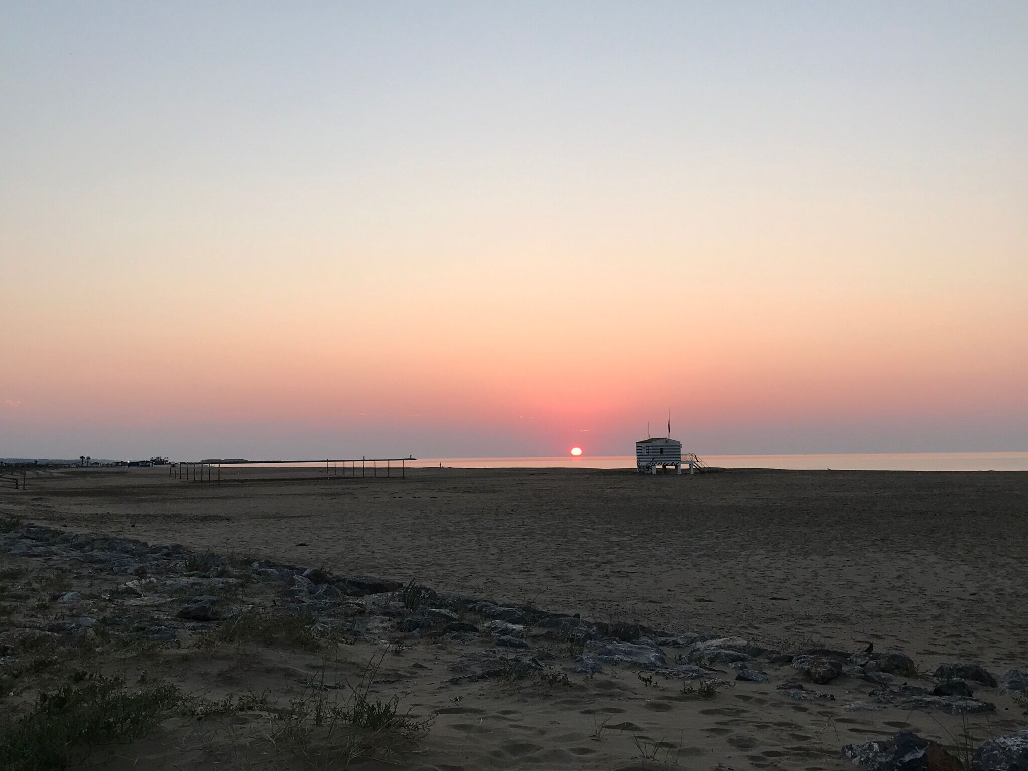 Una playa con una torre de salvavidas y un muelle que se adentra en el agua.