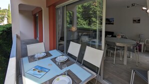A dining area with a glass table and chairs, a view of the outdoors, and a small table with a lamp. - Central Arcachon - Charming 2-BR for 4 with Balconies & Parking (Arcachon)