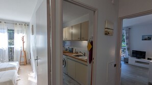 A modern kitchen with wooden cabinets, a sink, and a dining area with a table and chairs. - Central Arcachon - Charming 2-BR for 4 with Balconies & Parking (Arcachon)