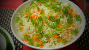 A bowl of rice with green and orange vegetables. - Hotel Gopika International (Panaji)