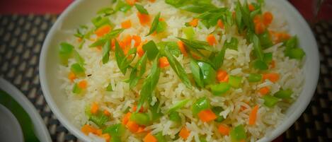 Un tazón de arroz con verduras verdes y anaranjadas.