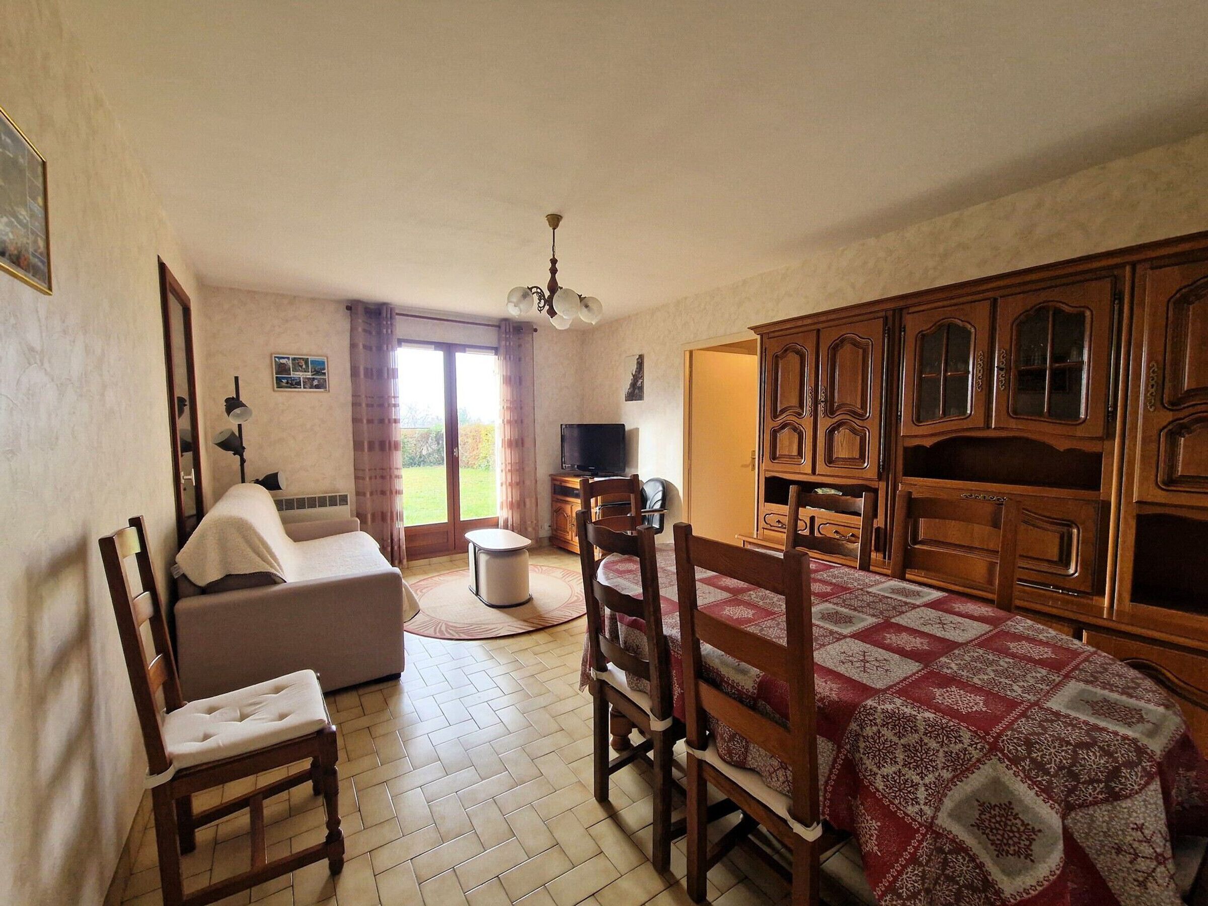 A cozy room with a dining table, chairs, a sofa, and a television.