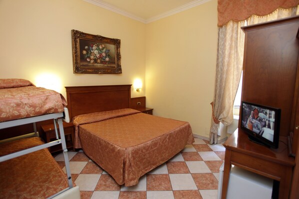 Una habitación de hotel con una cama, televisión, un cuadro en la pared y piso a cuadros.