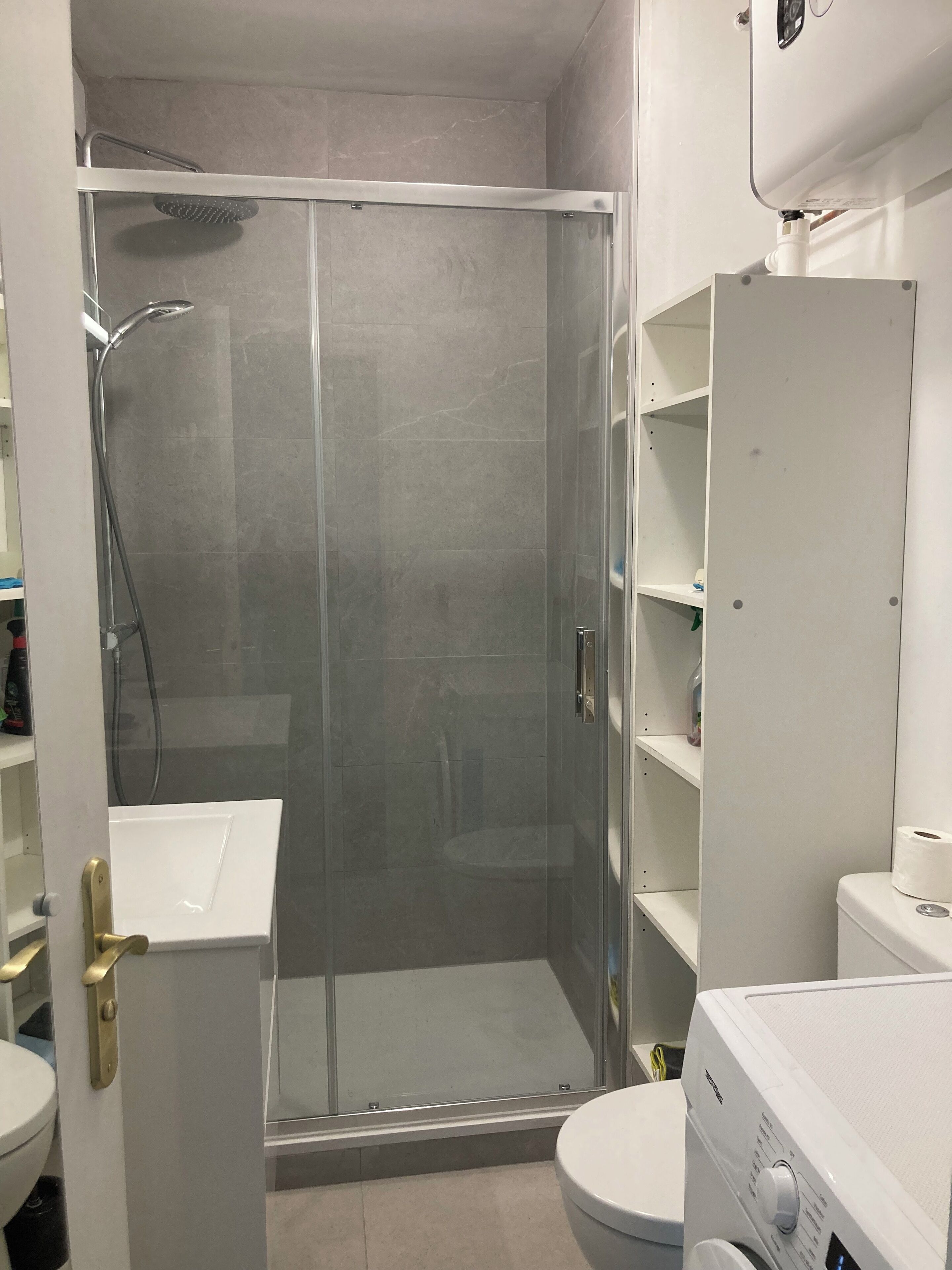 Un bagno moderno con cabina doccia in vetro, lavandino bianco e water.