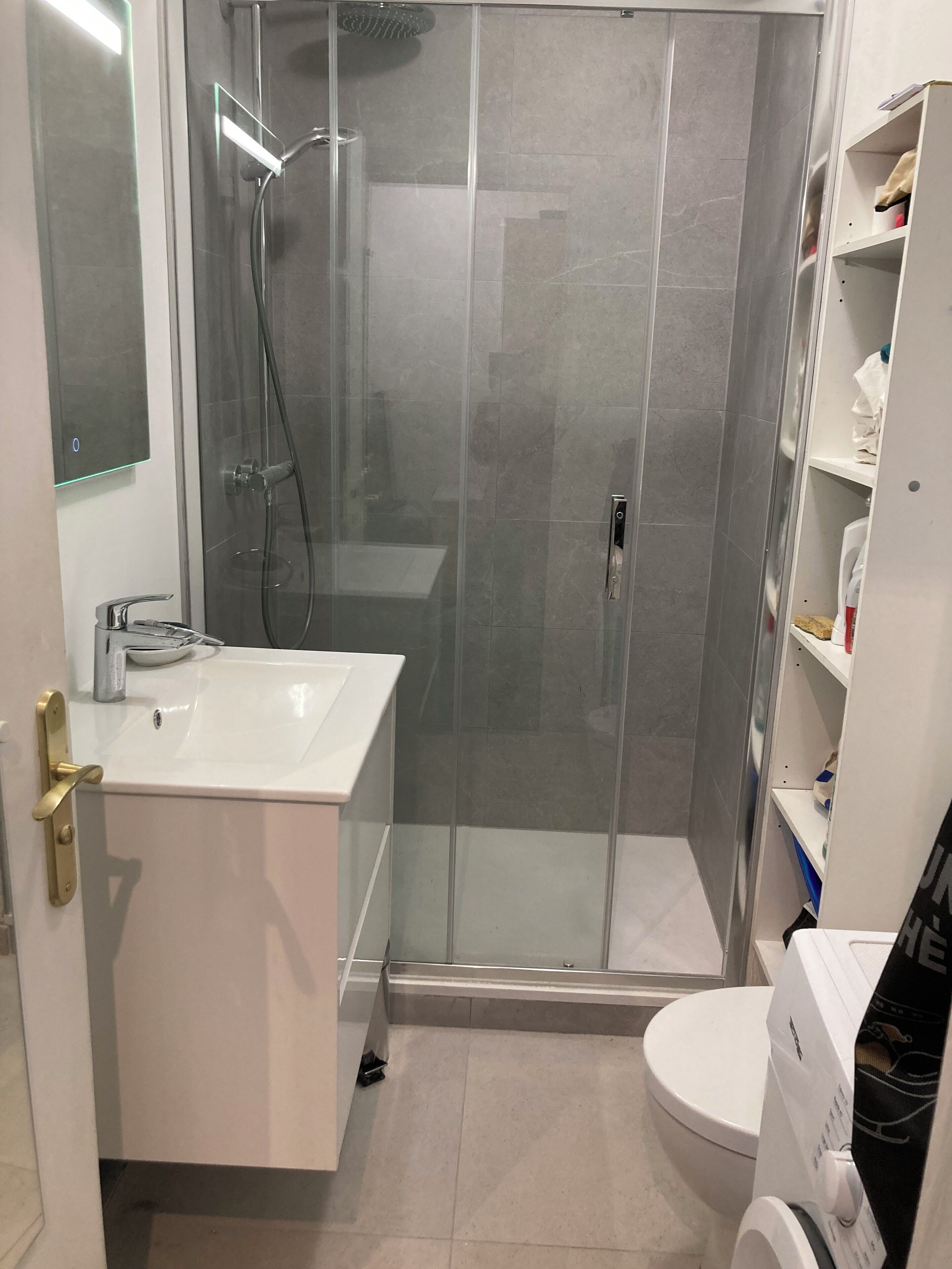 Une salle de bain avec une douche à parois de verre, un lavabo blanc et des toilettes.
