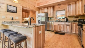 Eine Holzhütte mit einer Küche, einer Granitarbeitsplatte, Edelstahlgeräten und Holzbarhocker.