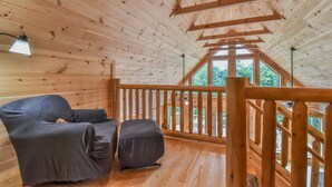 Eine Holzhütte mit Balkon, einer Couch und einem kleinen Tisch.