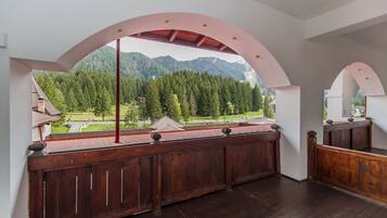 A balcony with a wooden railing overlooking a mountainous landscape.