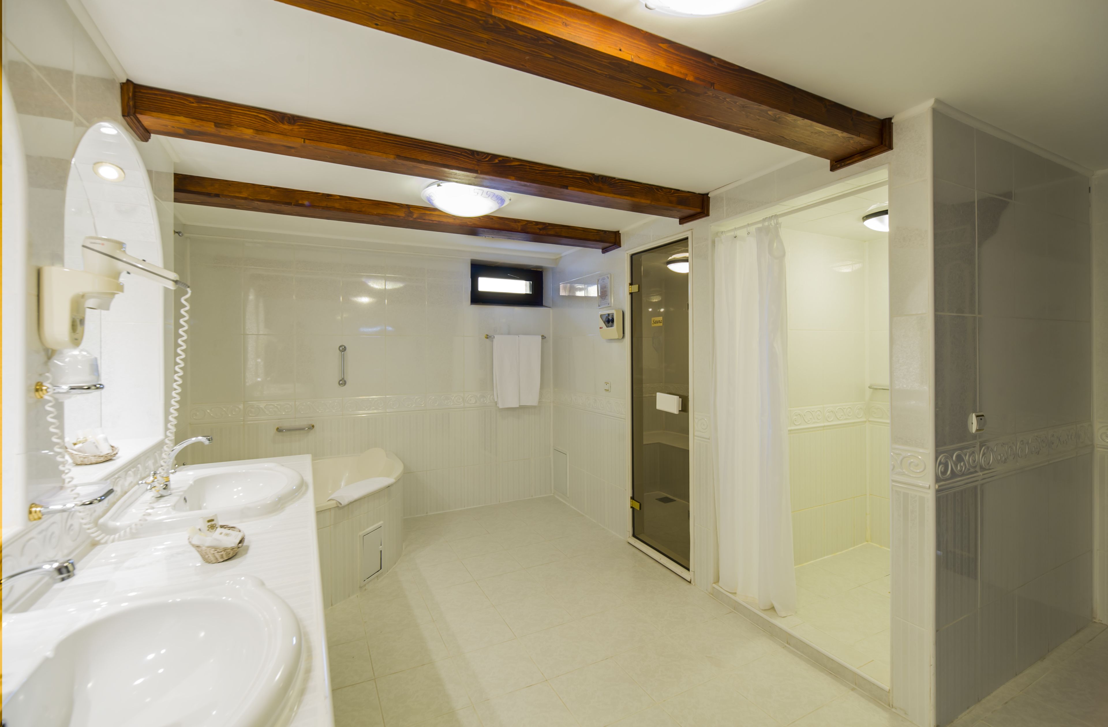 A bathroom with two sinks, a toilet, a shower, and a glass door leading to a walk-in shower.