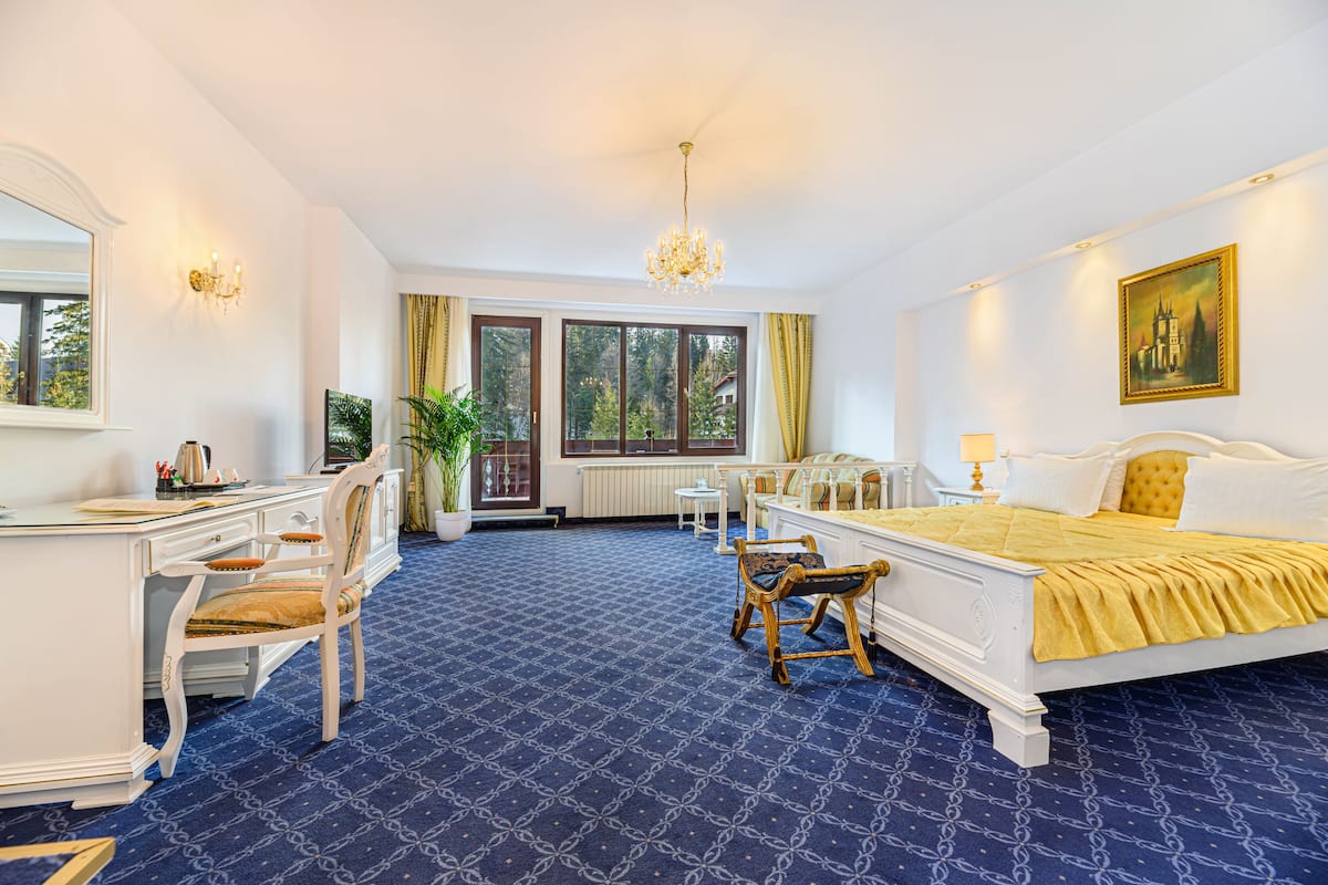 Habitación de hotel con una cama grande, un escritorio, una silla, una mesita y una planta en maceta.