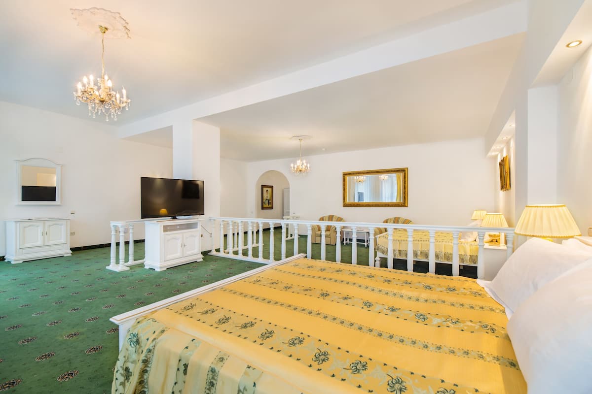 Un espacioso dormitorio con una cama grande, televisión, candelabro y balcón con vistas.