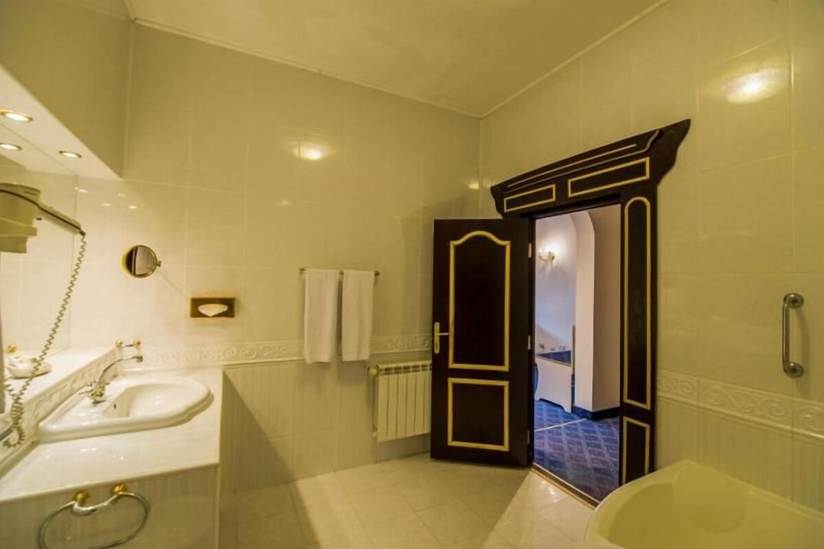 Un baño con lavamanos, espejo, toallero y bañera.