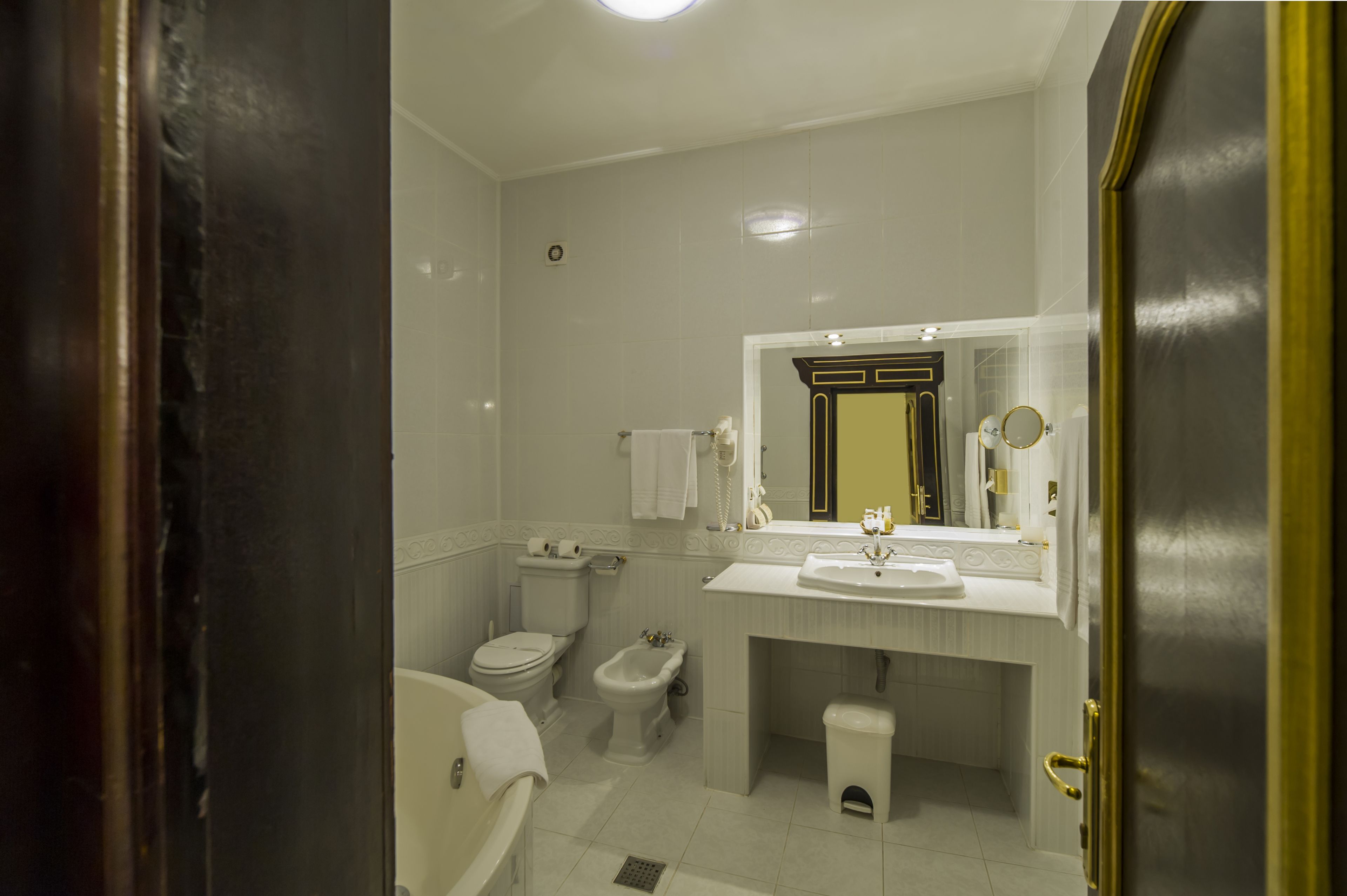 Un baño con inodoro, bidé, lavabo y espejo.