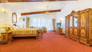 A spacious bedroom with a large bed, a wooden wardrobe, a television, and a chandelier.