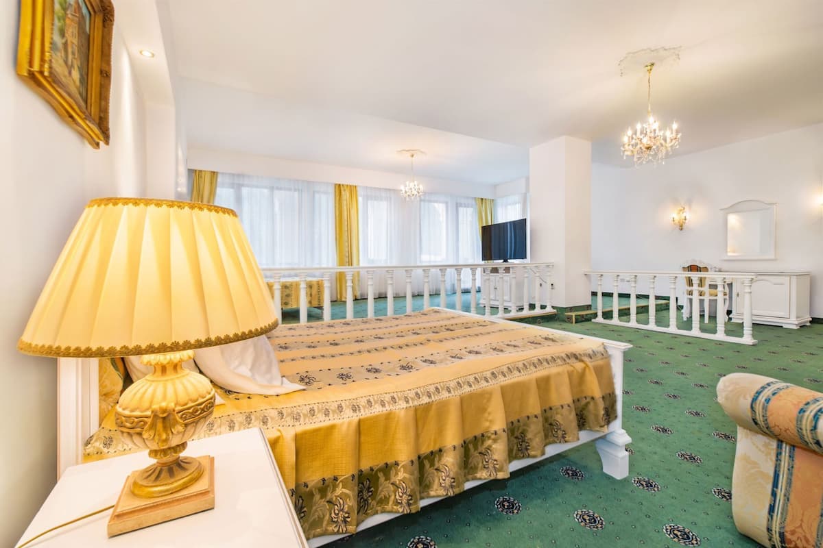 Habitació d'hotel amb llit, làmpada, televisió, balcó i un lampadari.