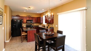 A spacious kitchen with dark wood cabinets, a central island, and a chandelier. - 4 bedroom house close to the Horse Park (Georgetown)