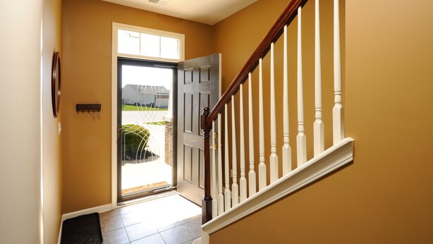 A hallway with a wooden staircase, a door leading outside, and a light fixture on the ceiling. - 4 bedroom house close to the Horse Park (Georgetown)