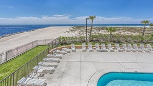 Ein Poolbereich mit Liegestühlen und Blick auf den Strand.