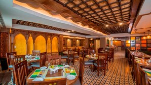 A restaurant with wooden furniture, patterned floor tiles, and a high ceiling with a wooden beam structure. - Lemon Tree Hotel Srinagar (Srinagar)