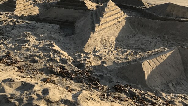 Ein Strand mit Sandformationen und Wellen.